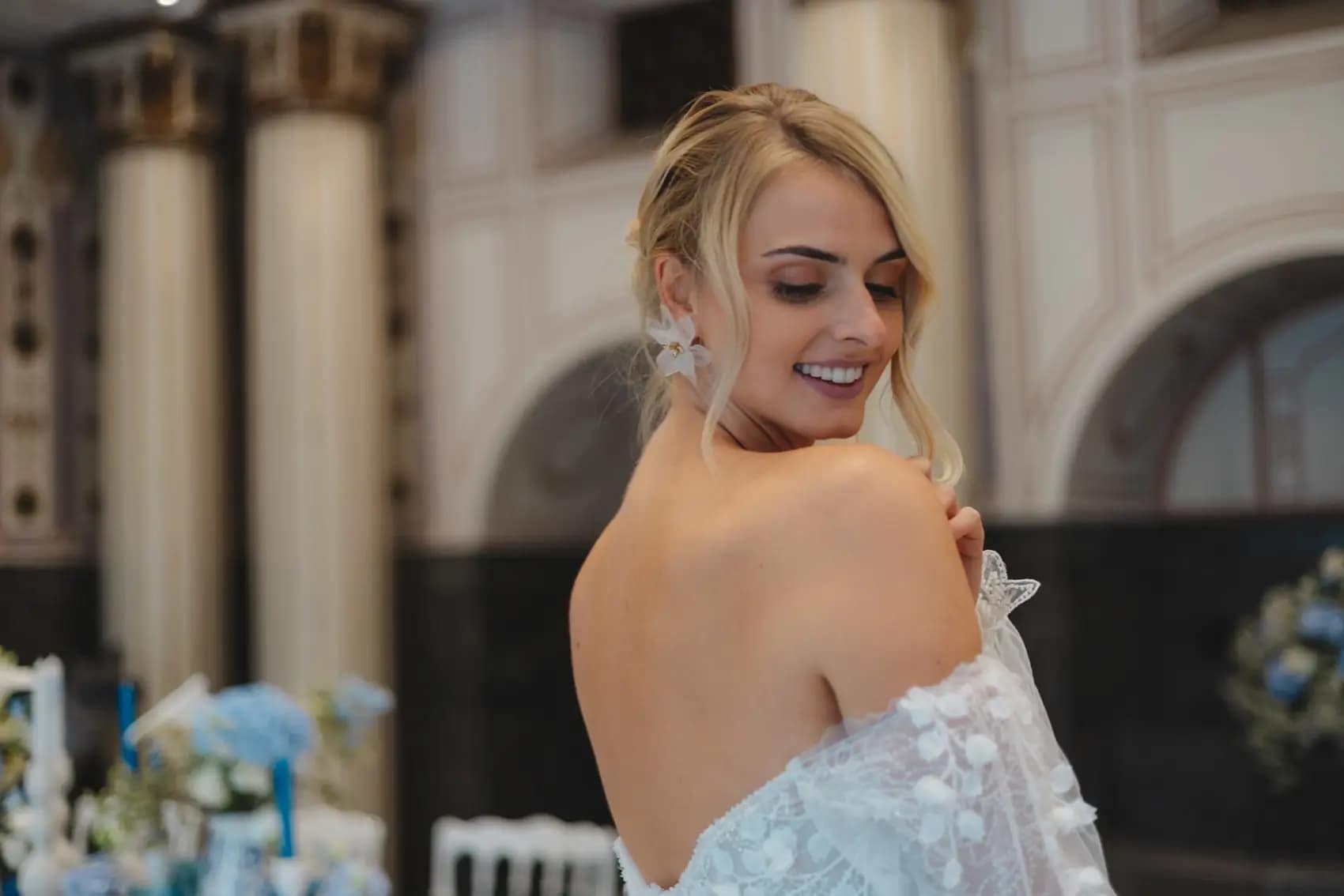 Sposa di spalle che sorride in una sala storica allestita in azzurro